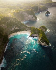Stunning aerial view of Bali's coastline with turquoise waters and lush cliffs.